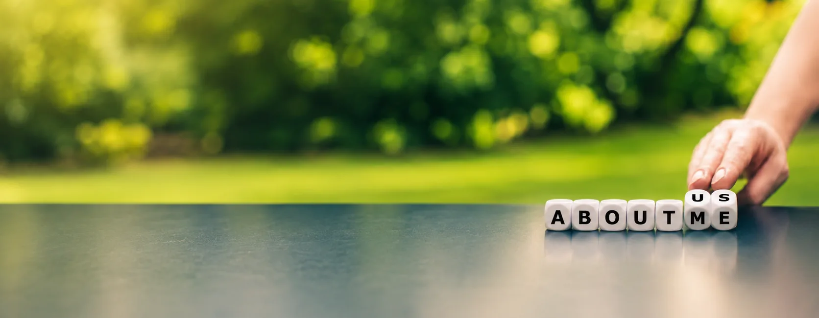 Dice spelling "About Us" as a hand flips the last letters